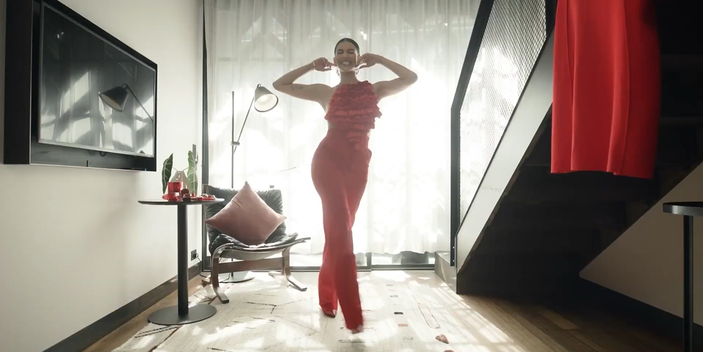 Woman in red styling poses with a magazine in a studio beauty portrait, showcasing a bright, confident smile for the Colgate Optic White campaign.
