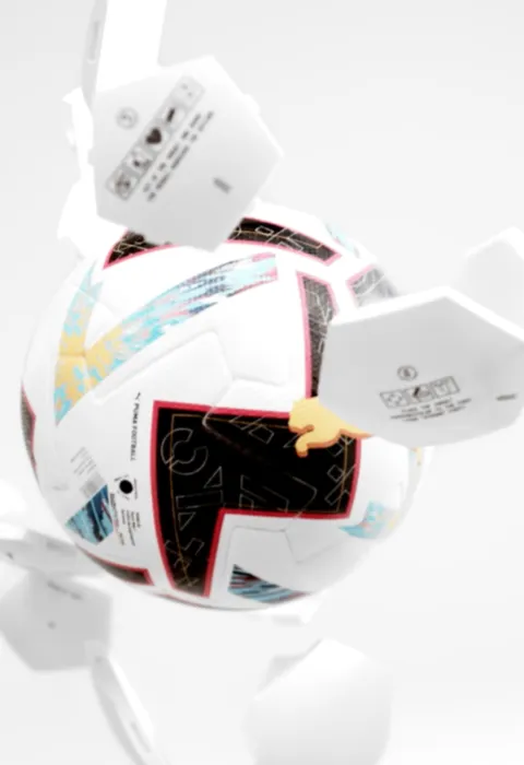 Football in mid air with parts flying off, positioned against a grey background. 