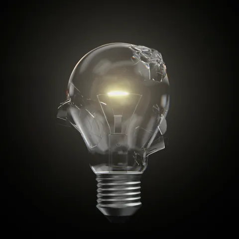 Cracked lightbulb still glowing, positioned on a black background. 