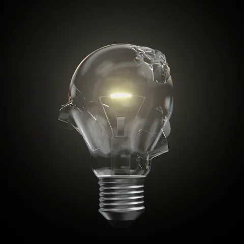 Cracked light bulb still glowing, positioned on a black background.