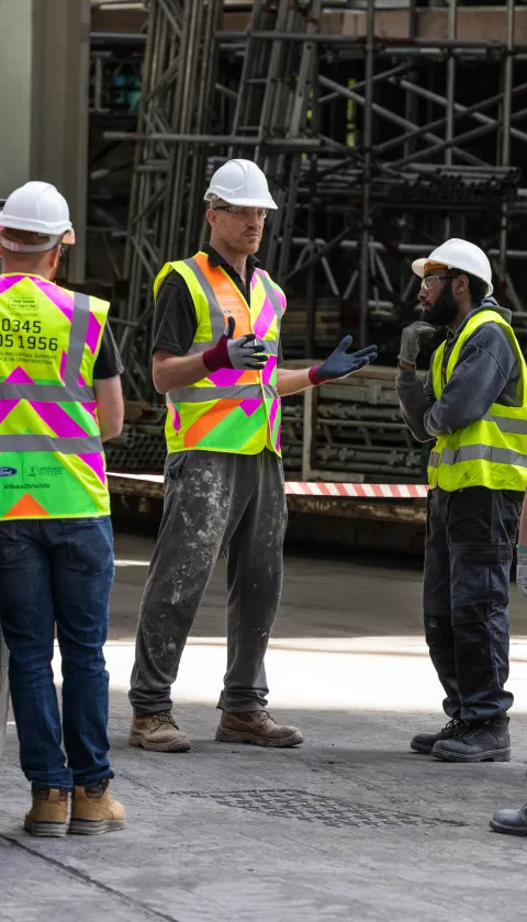 Group of men in high vis on building site. 