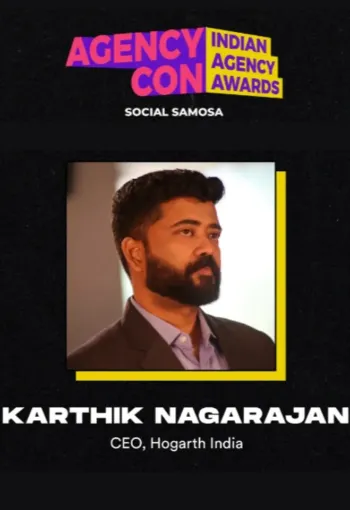 Man with black hair and a beard, looking to the right while posing for a headshot.